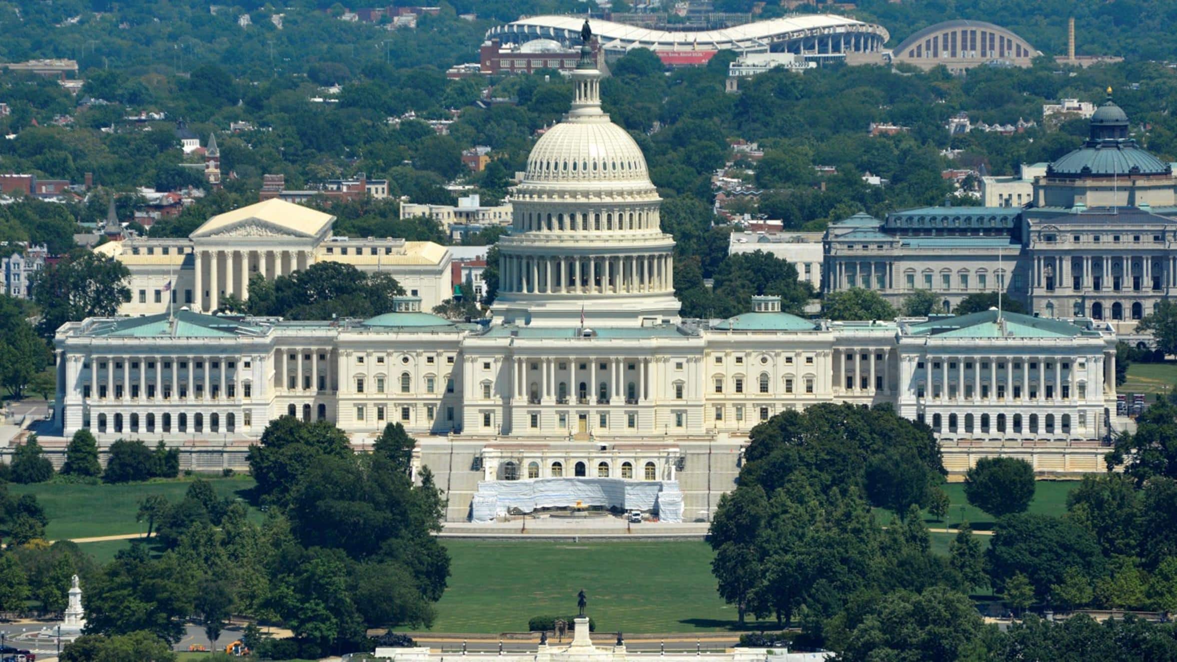 Aerial view of the US Capitol building in Washington DC with surrounding greenery.